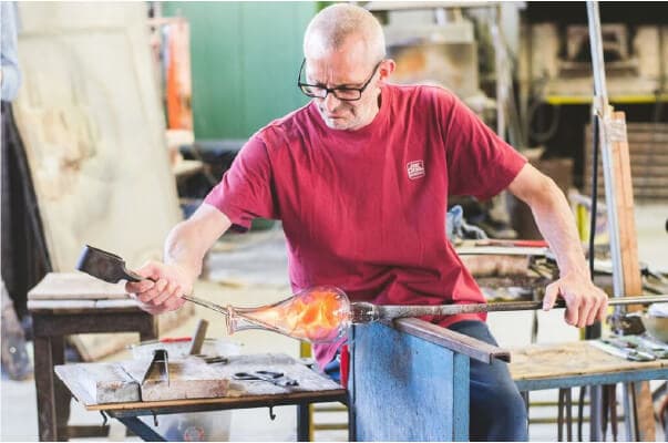 Vetraio esperto che lavora il vetro fuso nel suo laboratorio